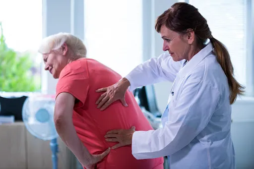 Chiropractor examining the lower back and hip of an older woman with hip pain