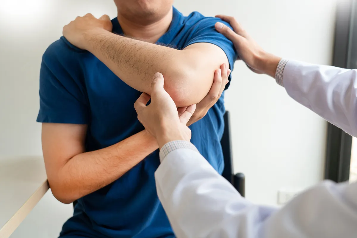 Chiropractor examining a patient’s shoulder and elbow during a chiropractic exam