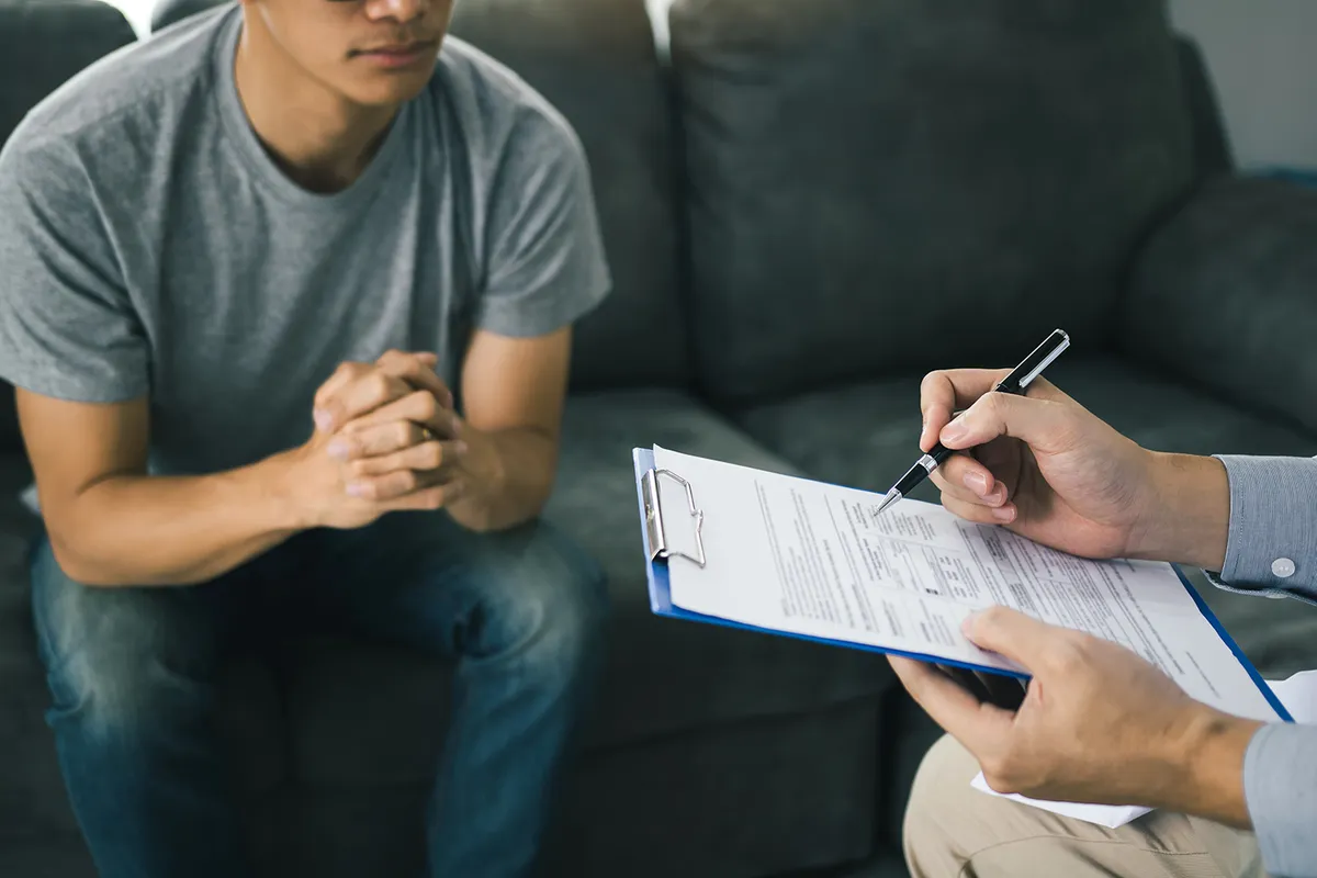 New patient on a couch while a staff member fills out intake forms on a clipboard