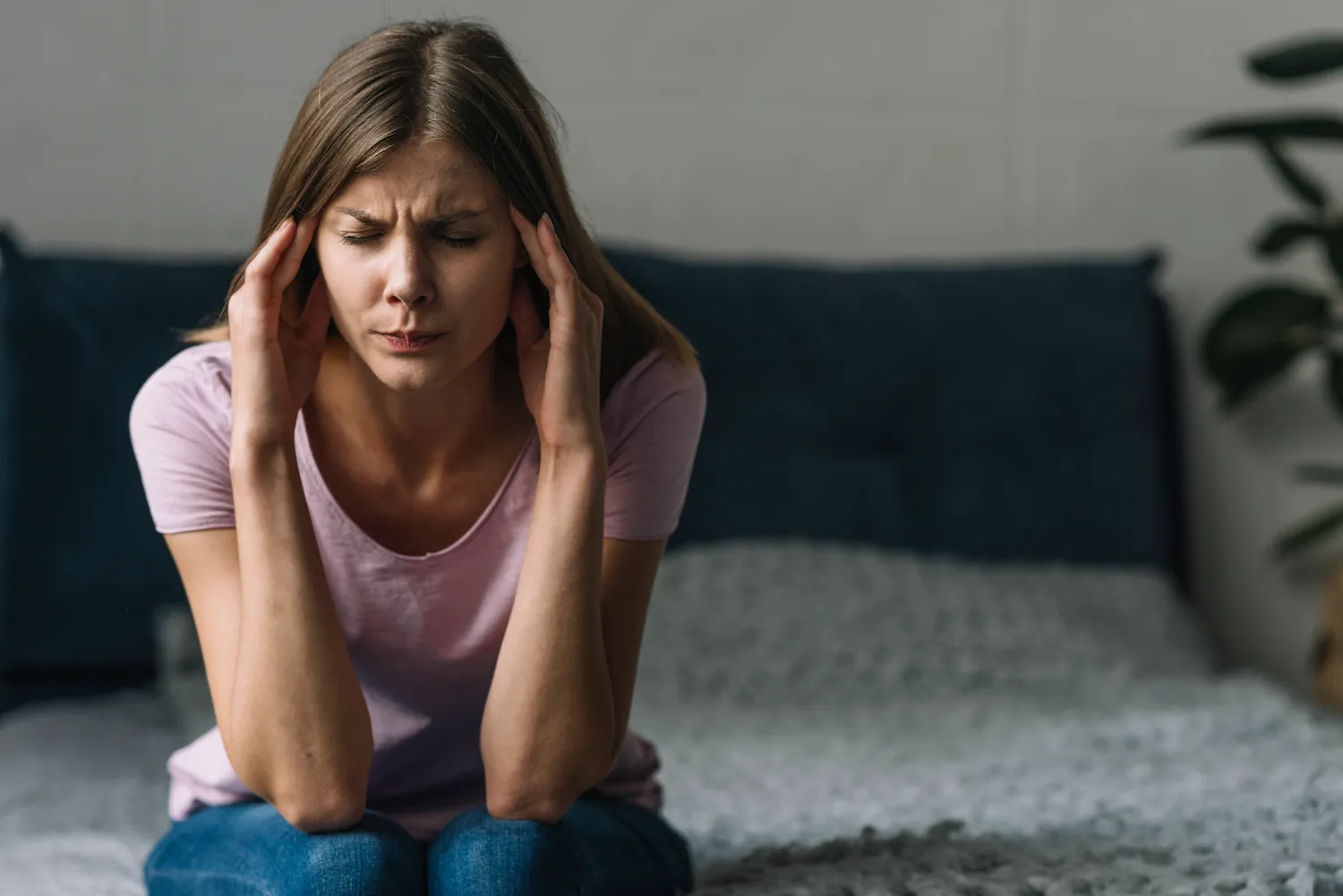 woman having a migraine, sitting in bed