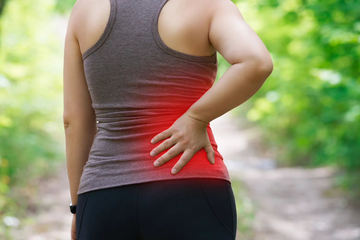 Woman holding her lower back from sciatica pain before seeing a chiropractor in Dubuque, IA